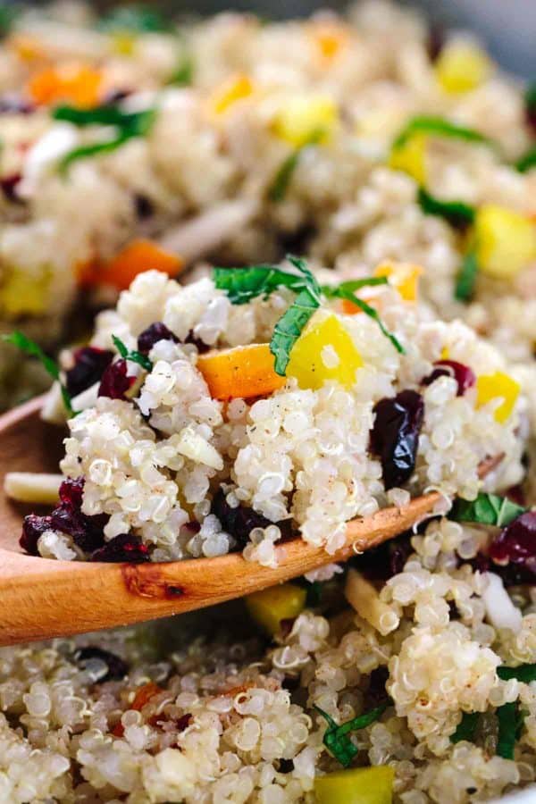 木匙子挖出与五颜六色的蔬菜和绿色装饰的奎奴亚藜