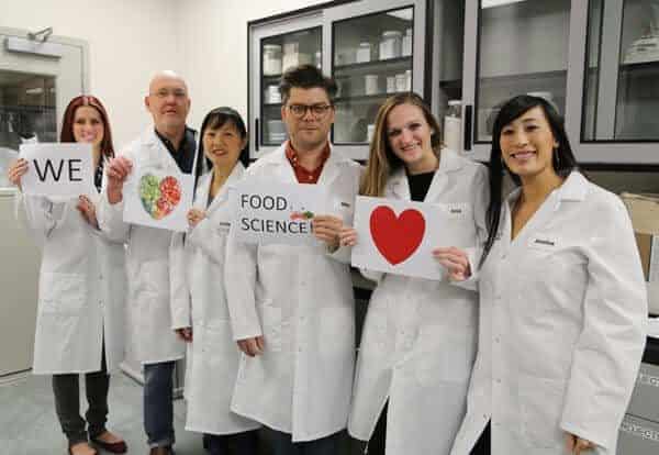 Jessica与工作朋友举起A:我们爱食品科学标志