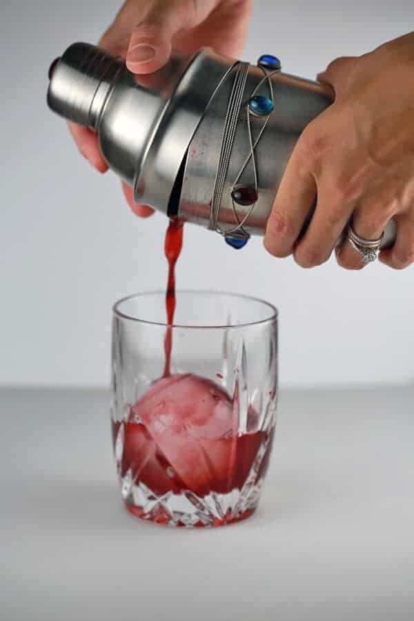 鸡尾酒振动器混合饮料并将其倒入玻璃杯中