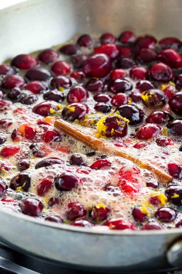 在炉子上用平底锅烹饪小红莓,橙子屑和肉桂棒