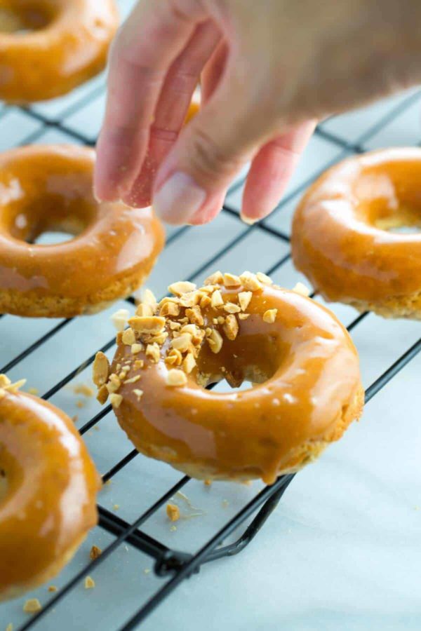 用手指在甜甜圈上撒碎花生