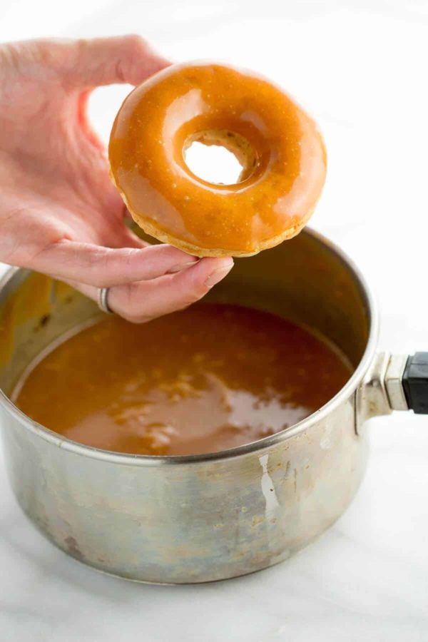 手里拿着一个刚蘸过焦糖酱的甜甜圈