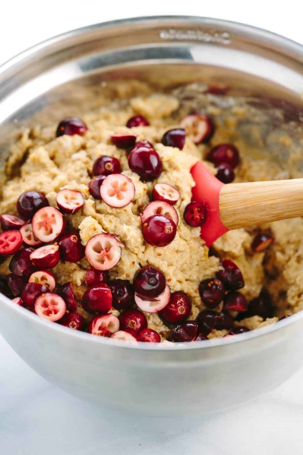 用刮刀将切好的蔓越莓和整个蔓越莓混合到松饼面糊中