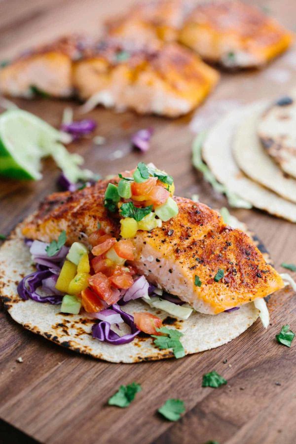 用芒果辣调味汁组装三文鱼炸玉米饼在砧板上