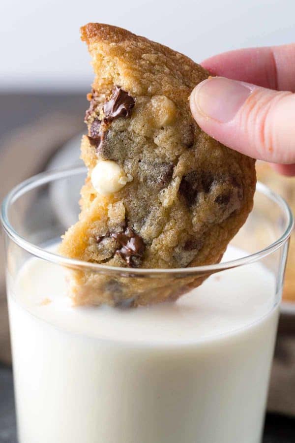 一个人把一块巧克力曲奇饼浸入一杯牛奶中