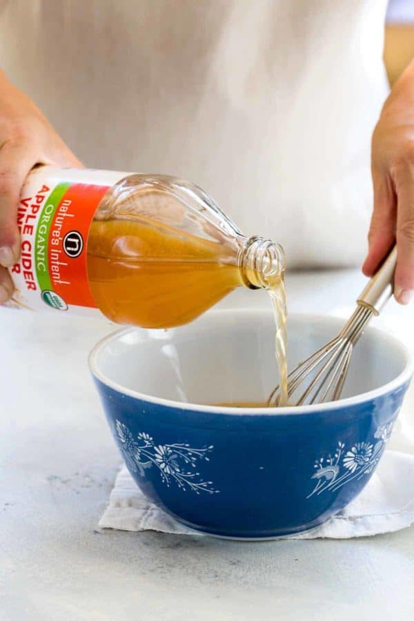 在一个蓝色碗的苹果汁醋倾吐制造鸡卤汁