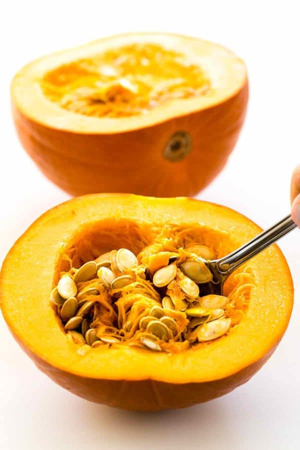 用银勺从切了一半的南瓜里挖出种子