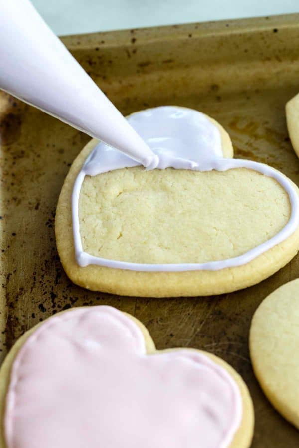 裱花袋在烤盘上的心形饼干上涂满糖霜