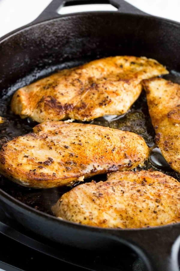 四个经验丰富的鸡胸肉在铸铁煎锅烹饪