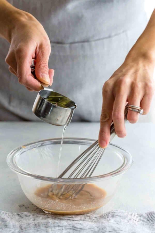 在玻璃碗里自制红酒醋沙拉酱的人