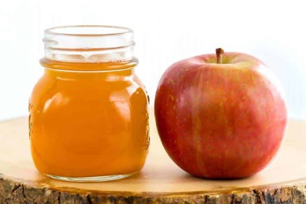 玻璃瓶子苹果汁醋在一个红色苹果旁边