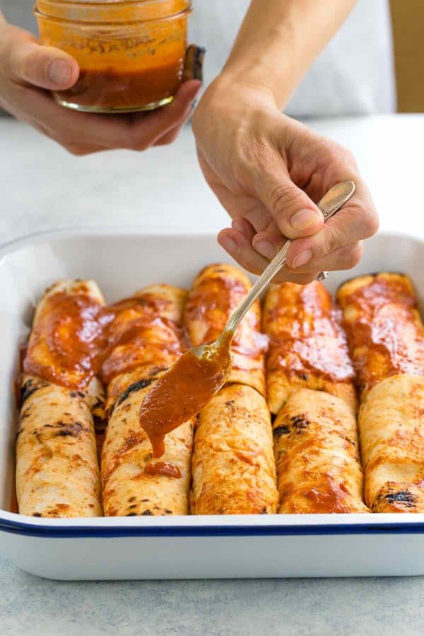 添加红色调味汁的人的照片向鸡enchiladas顶部