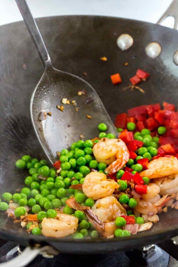 虾,豌豆和红色甜椒在炒锅上烹饪