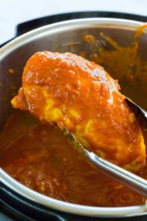 钳子在立即锅前举起鸡胸肉