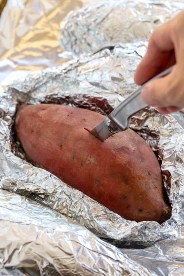 将一把刀刺入烤的甘薯以检查捐款