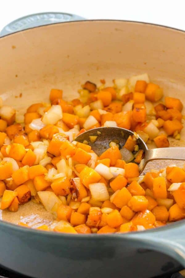 烹调在一个蓝色荷兰烤箱的胡桃南瓜立方体