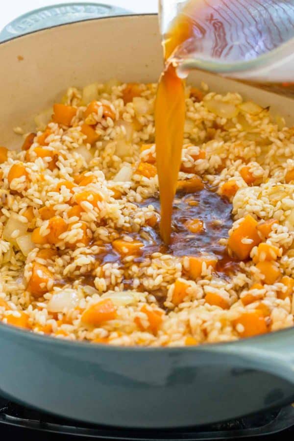 倾吐蔬菜股票液体到荷兰烤箱里用米和胡桃南瓜