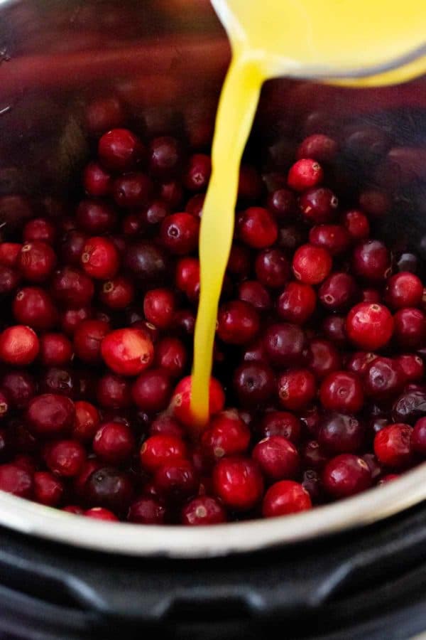 橙汁被倒入一个充满蔓越莓的立即锅中