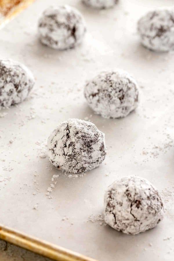 在烤盘上铺上烤盘纸,将饼干面团球卷起来