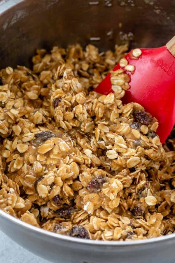 燕麦饼干面团与一个红色抹刀混合在一个金属碗里