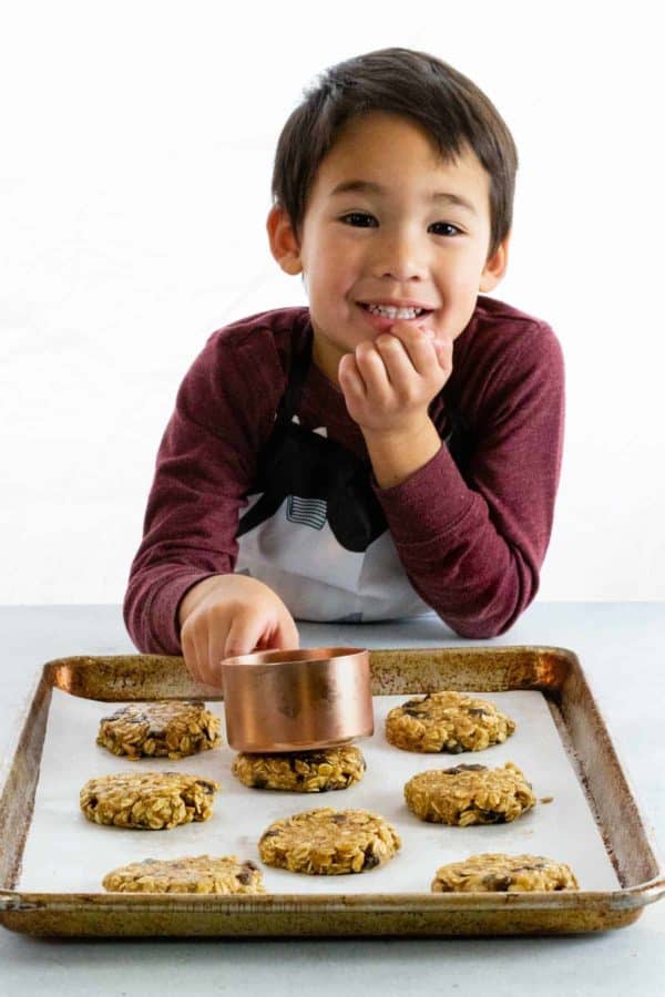 按一下测量杯子后面的小男孩反对曲奇饼,平衡面团球