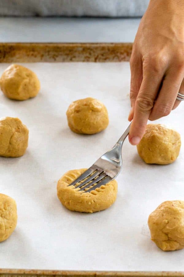 按叉子的人在板料盘的花生酱曲奇饼面团球