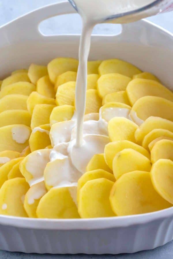 在砂锅菜中,把奶油倒在切片的土豆上