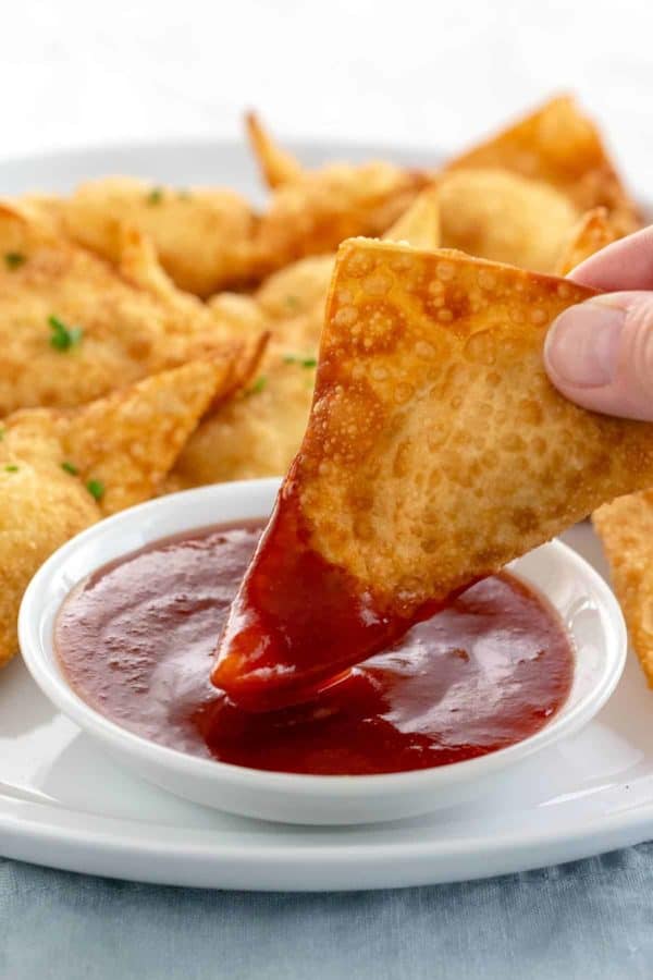 将炸馄饨浸入一小碗甜酸酱中