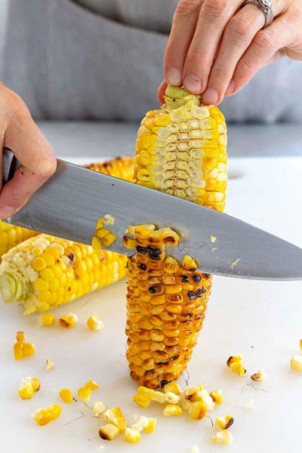用刀从玉米棒上切下烤玉米粒