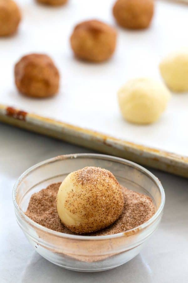 在一小碗肉桂和糖中滚动一个面团球