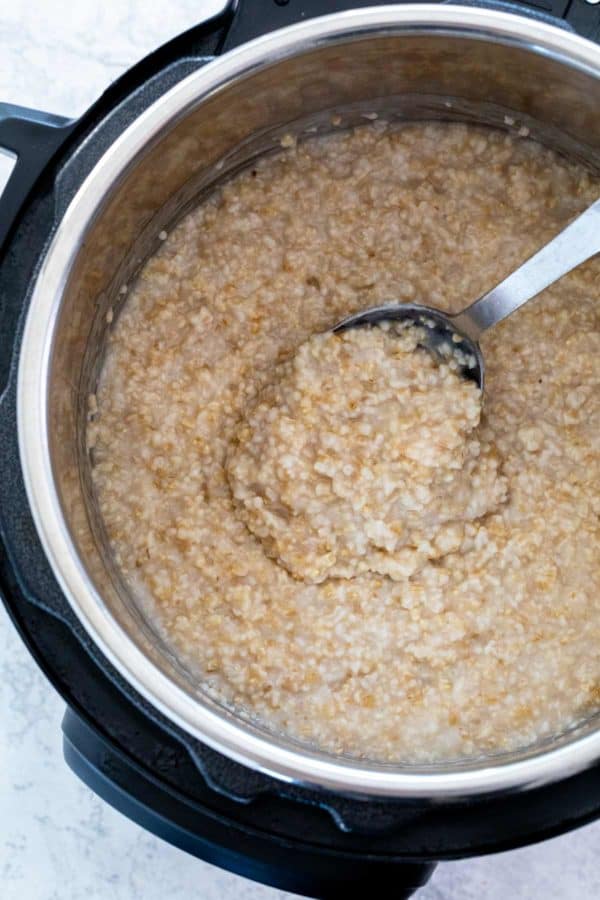 顶视图的勺子搅拌煮熟的燕麦在压力锅里