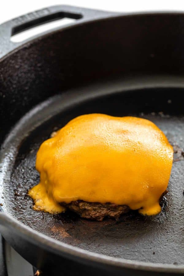 奶酪在汉堡上融化,肉饼在平底锅里煮