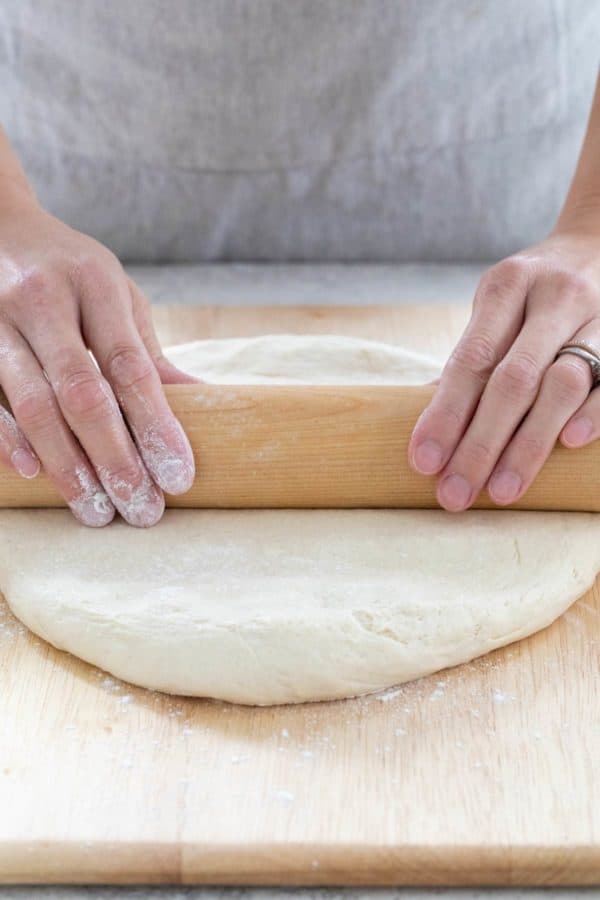 在撒了面粉的表面上擀面团的人