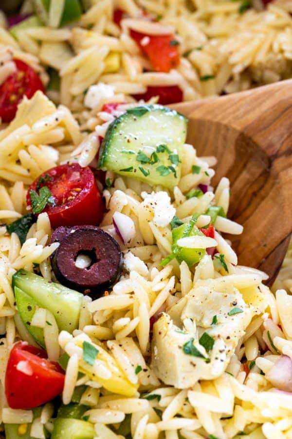 木制勺子搅拌意大利面沙拉的特写镜头