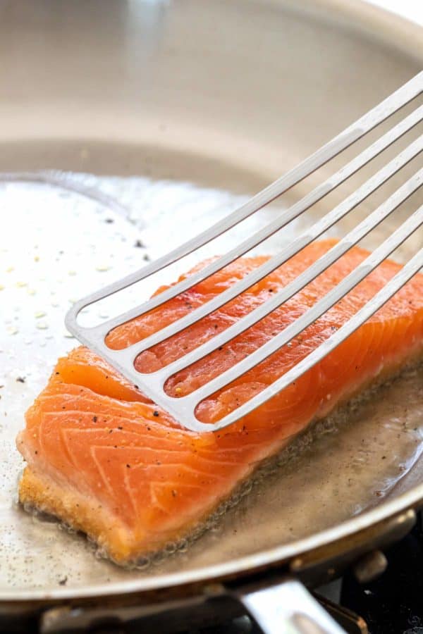 把鱼铲压在煎鲑鱼片上