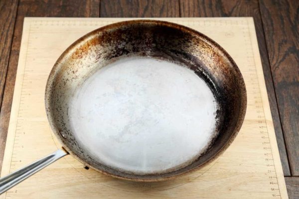 A dirty stainless steel pan before being cleaned and polished