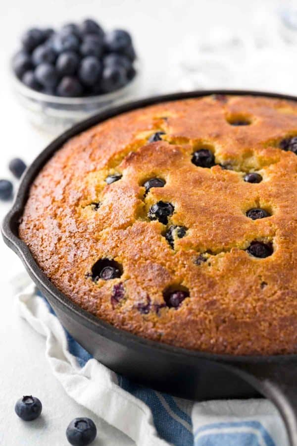 Cast iron skillet cornbread with blueberries cooling after being baked in the oven