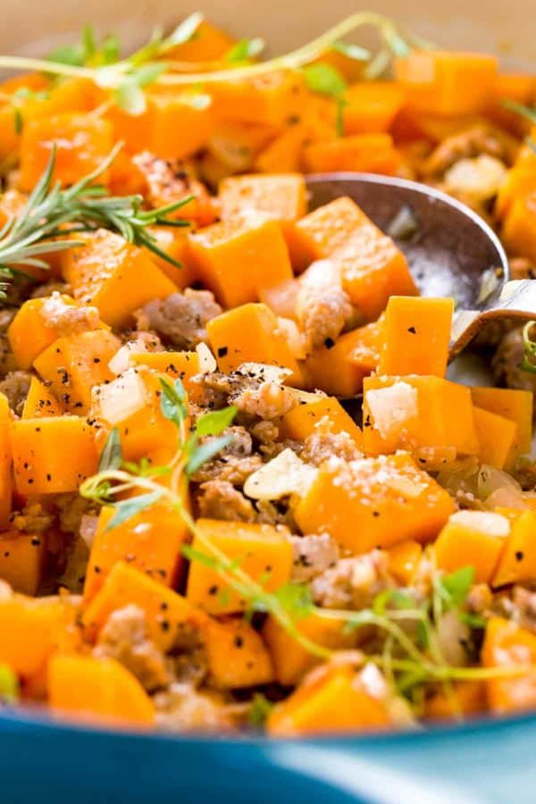 橙色胡桃南瓜和地面意大利香肠的立方体片断在一个蓝色罐。