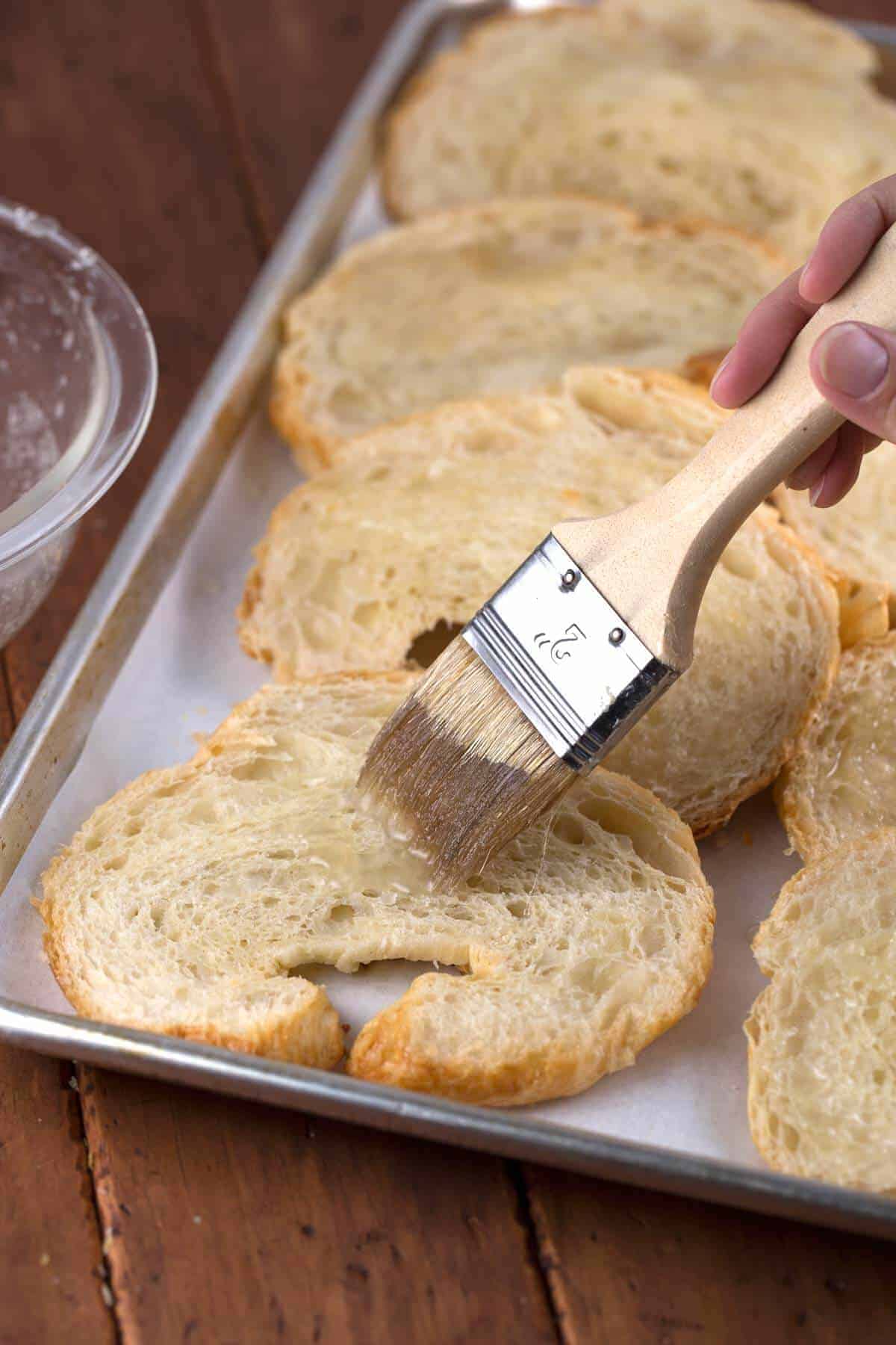 brushing butter onto slices of croissant