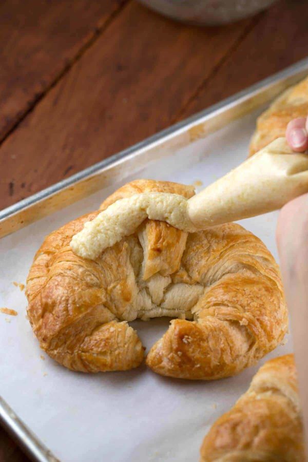 pipping cream on the top of a croissant