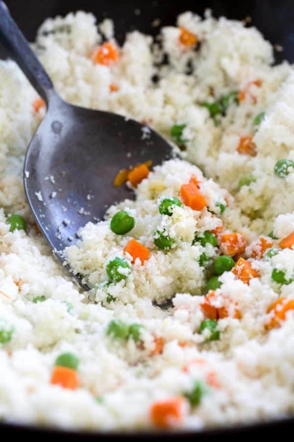 金属铲将花椰菜、米饭和蔬菜放入锅中搅拌。