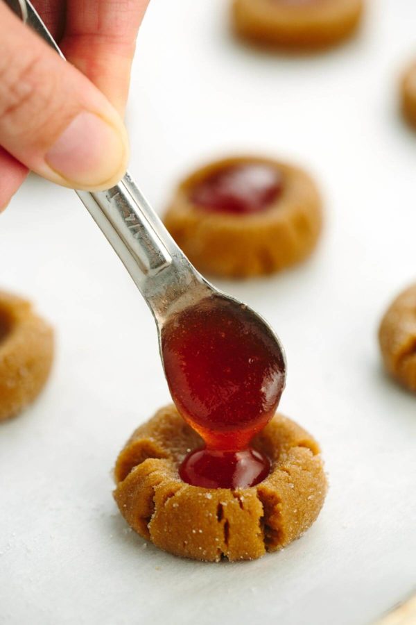 茶匙红果酱被放在饼干的拇指上