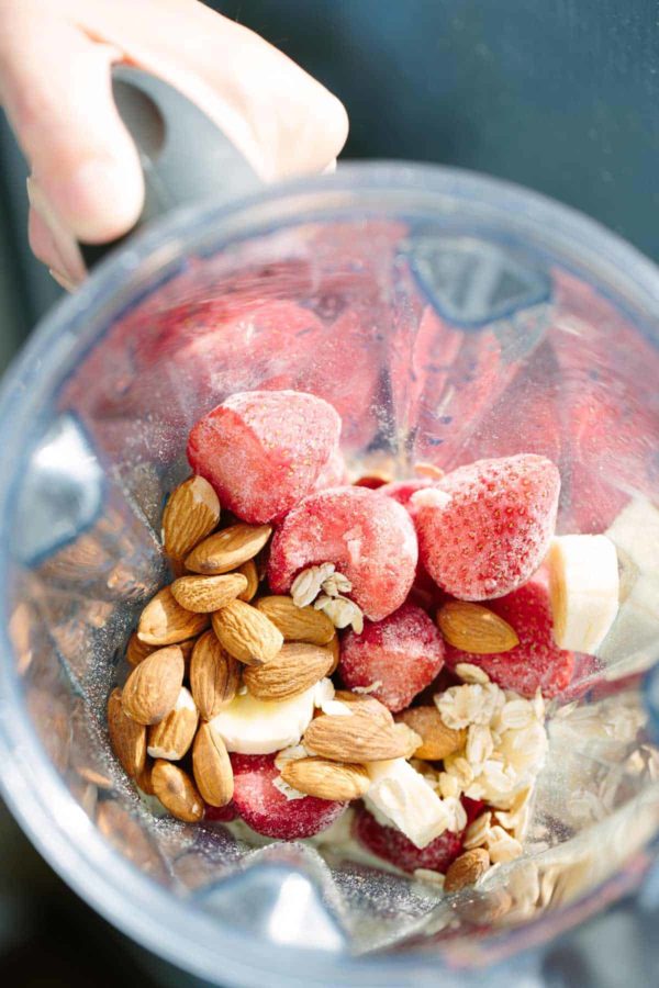 冰冻草莓放在搅拌机杯中，还有杏仁和香蕉片