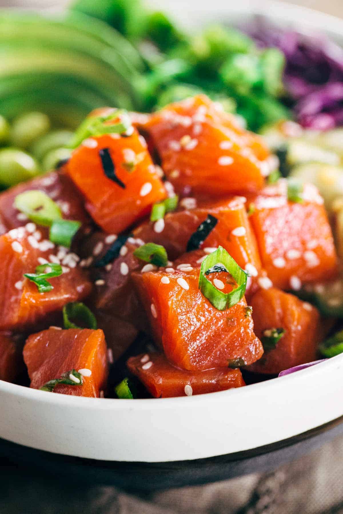 关闭显示芝麻籽的照片冠上在辣红鸡肉三文鱼立方体