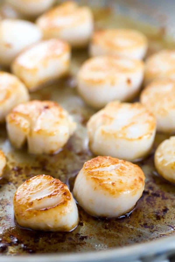 几个烤扇贝在煎锅中烹饪