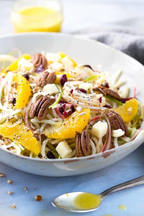 一碗苹果沙拉，上面有核桃和橘子片