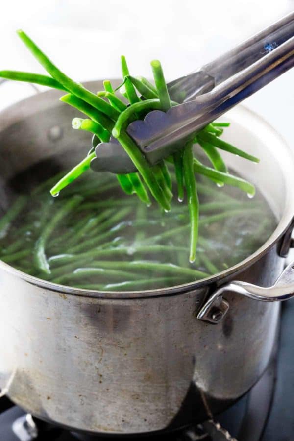 从一个热的沸腾的水中抓住青豆的金属钳