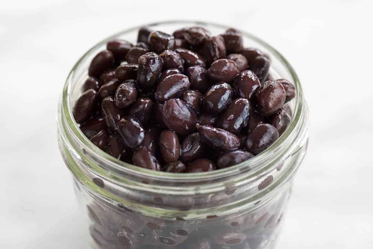 Black beans in a clear glass jar.