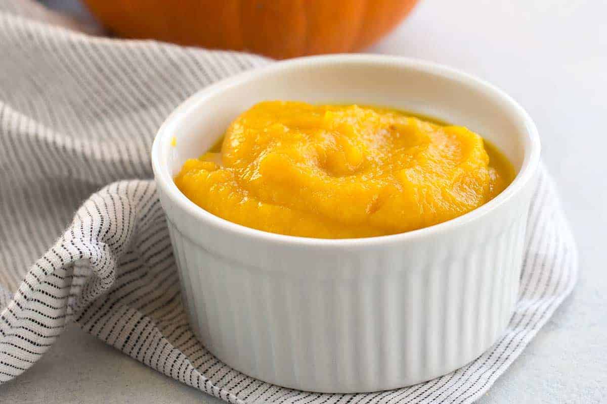 Bright orange pumpkin puree in a white ramekin.