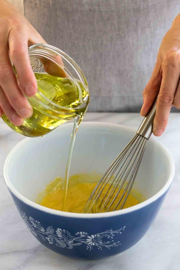 倒一个清楚的瓶子油的人入一碗混合的鸡蛋洗涤